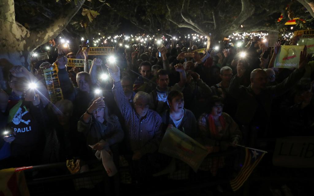 People hold their mobile phones during a gathering in support of the members of the dismissed Catalan cabinet after a Spanish ju